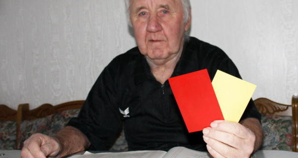 Horst Jendrasch sitzt am Tisch und hält eine gelbe und rote Karte in der Hand
